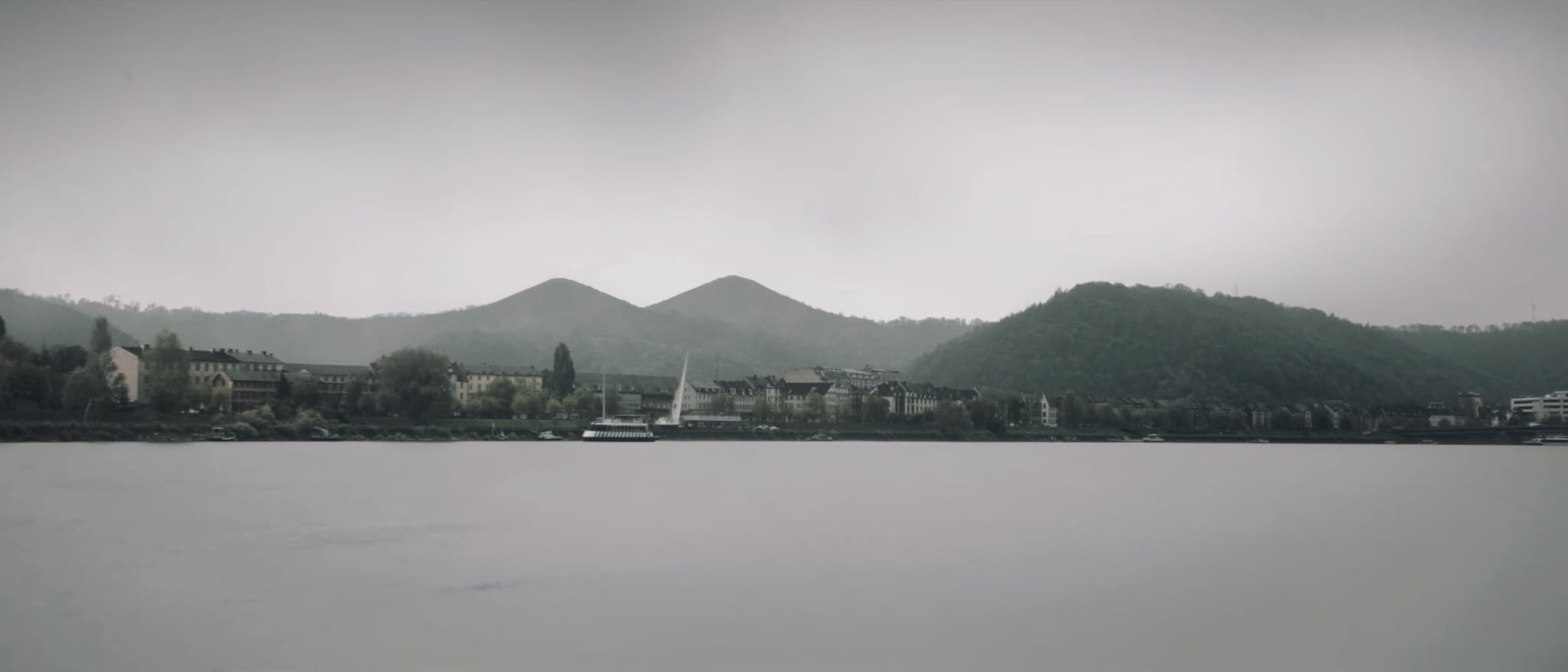 Rajna, grad uz obalu, iza njega zaobljeni vrhovi Zibengebirgea