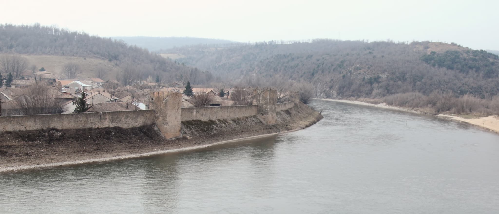 Reka kroz nizak grad, zaobljena brda na horizontu