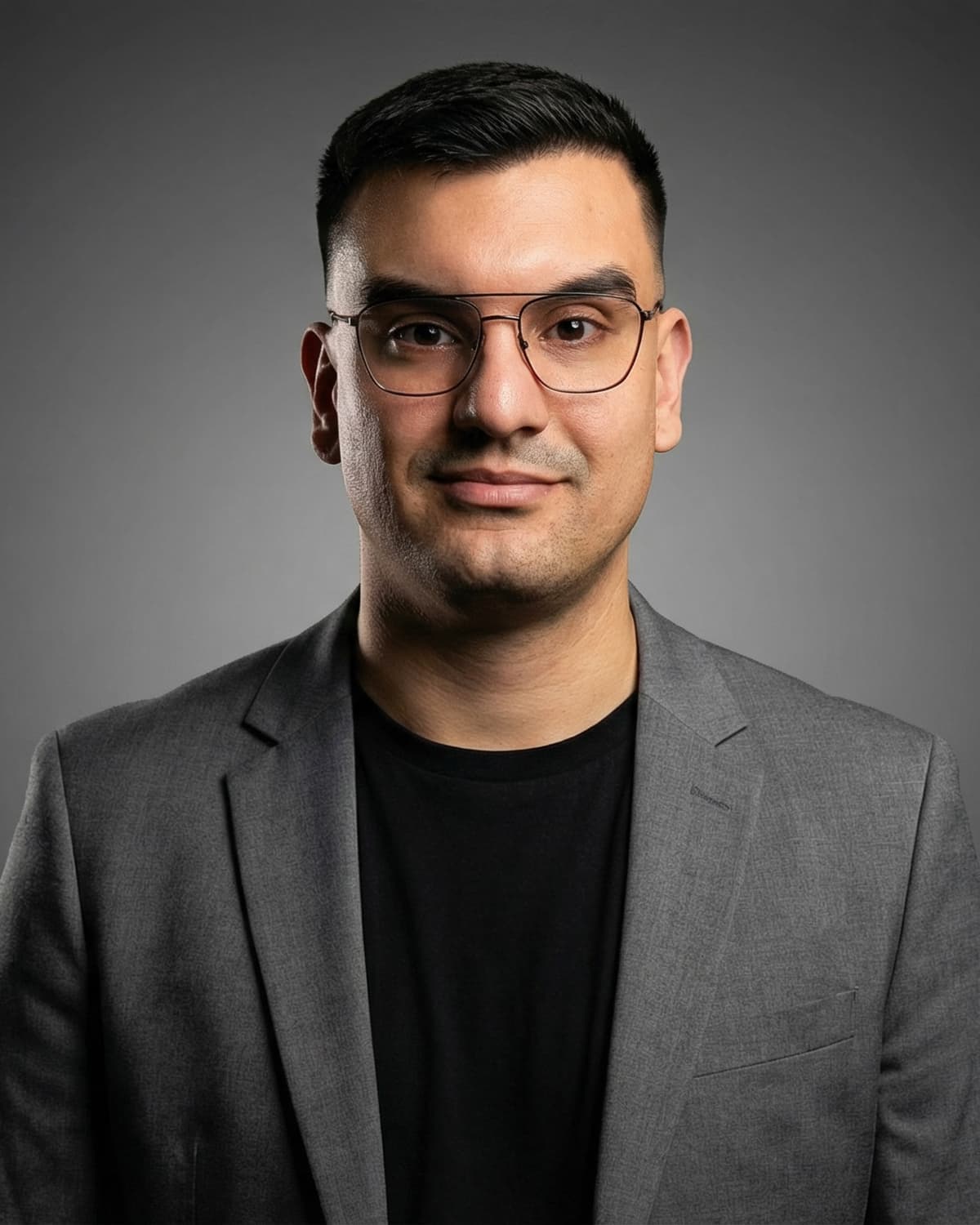 Damjan Savić, frontalni studijski portret ispred sive pozadine, sivi sako preko crne majice